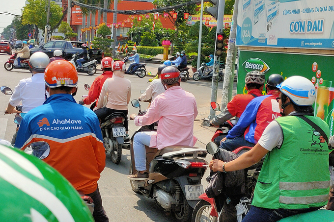 Tài xế của hàng loạt hãng giao hàng, gọi xe chờ đèn đỏ tại ngã tư Cách Mạng Tháng Tám - Nguyễn Đình Chiều, quận 3, TP HCM chiều 12/5. Ảnh: Viễn Thông