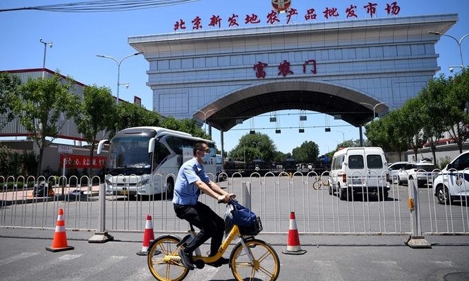 Nhân viên an ninh đạp xe qua khu chợ Tân Phát Địa bị đóng cửa ở Bắc Kinh hôm 14/6. Ảnh: AFP.