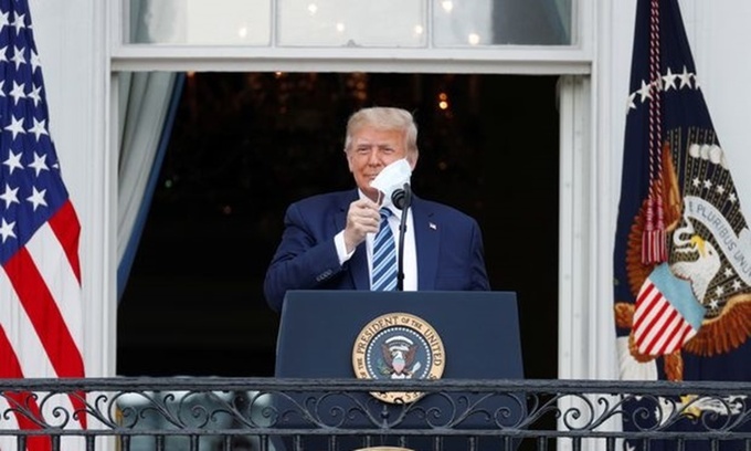 Tổng thống Trump cởi khẩu trang, chuẩn bị phát biểu trước đám đông người ủng hộ từ ban công Nhà Trắng ngày 10/10. Ảnh: Reuters.