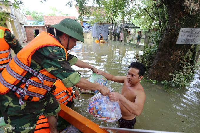 Quân đội dùng canô vượt lũ phát lượng thực cho người dân xã Tam Đàn, huyện Phú Ninh trong sáng 12/10. Ảnh: Đắc Thành