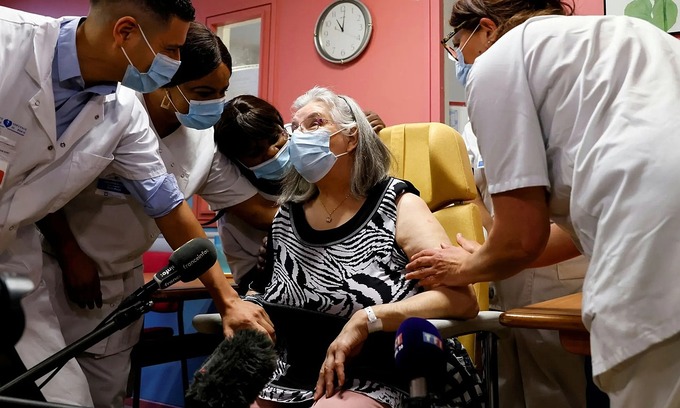 Nhân viên y tế trò chuyện với Mauricette, 78 tuổi, người đầu tiên được tiêm chủng ở Pháp. Ảnh: Reuters