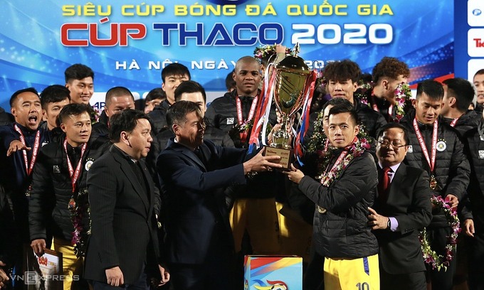 Phó tổng cục trưởng Tổng cục TDTT Trần Đức Phấn trao Siêu Cup cho đội trưởng Văn Quyết. Ảnh: Lâm Thỏa