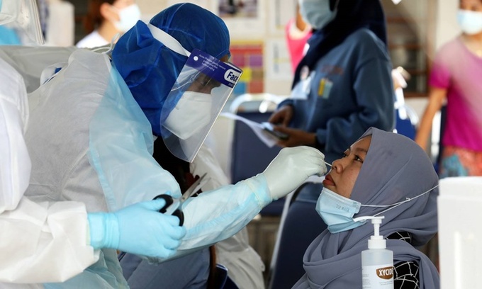 Nhân viên y tế lấy mẫu xét nghiệm Covid-19 cho một người dân ở thành phố Kelang, Malaysia, hồi tháng 11/2020. Ảnh: Reuters.