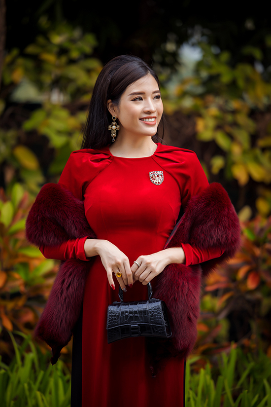 Phan Hoàng Thu kết hợp áo dài nhung đỏ cách điệu với khăn lông, túi Balenciaga và khuyên tai Versace. Cô có bộ sưu tập túi hiệu từ hàng chục đến hàng trăm triệu đồng mỗi chiếc.