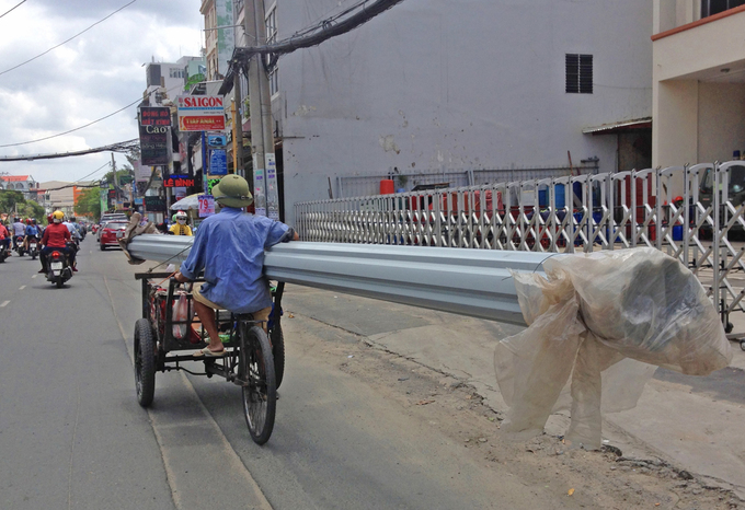 Người đàn ông chạy xe ga gác chở tôn cồng kềnh trên đường Phan Văn Trị, quận Gò Vấp, năm 2020. Ảnh: Gia Minh.