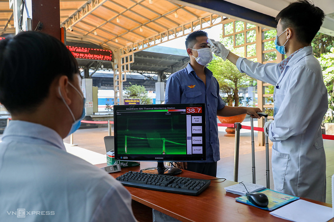 Nhân viên y tế tiến hành đo thân nhiệt cho hành khách tại ga Sài Gòn. Ảnh: Quỳnh Trần