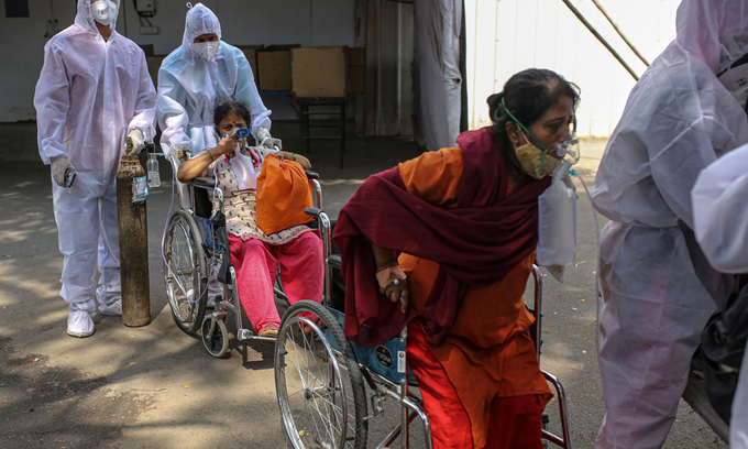 Nhân viên y tế hỗ trợ bệnh nhân Covid-19 bên ngoài một trung tâm cách ly ở Mumbai hôm 27/4. Ảnh: Bloomberg.